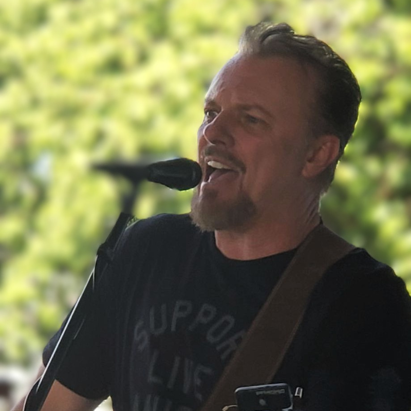 close up shot of a man live music performer. Greenery in the backdrop.